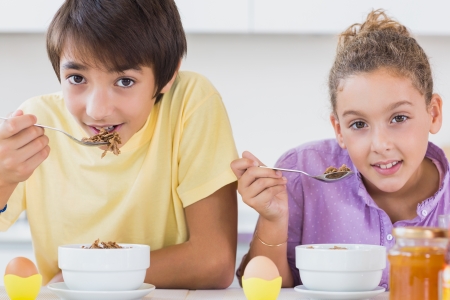 Happy siblings having breakfast in kitchenの写真素材