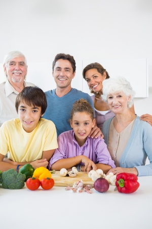 Multi generation family smiling in kitchen beside chopping boardの写真素材