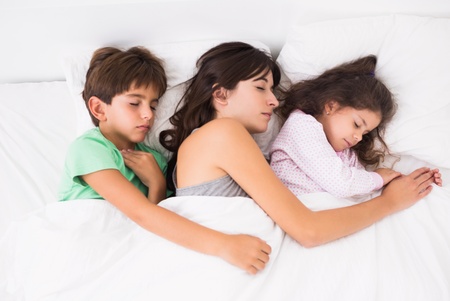 Mother asleep with her children in bed