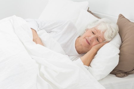 Aged woman sleeping on the bedの写真素材