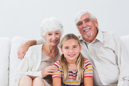 Granddaughter with grandparents smiling on couchの写真素材