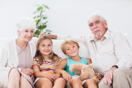 Smiling children with their grandparents on the couchの写真素材