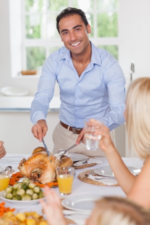 Smiling man carving the turkey at thanksgivingの写真素材