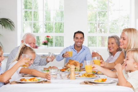 Smiling family toasting at thanksgiving at the dinner tableの写真素材