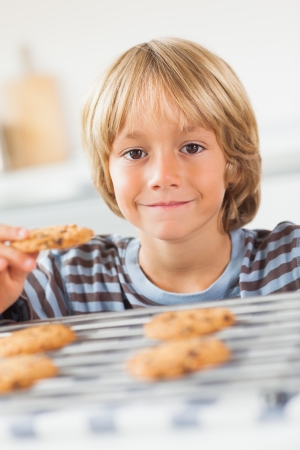 Smiling boy holding a cookie in the kitchenの写真素材
