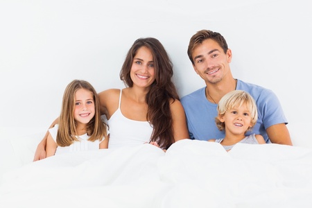 Cheerful family lying on a bed together in the bedroomの写真素材