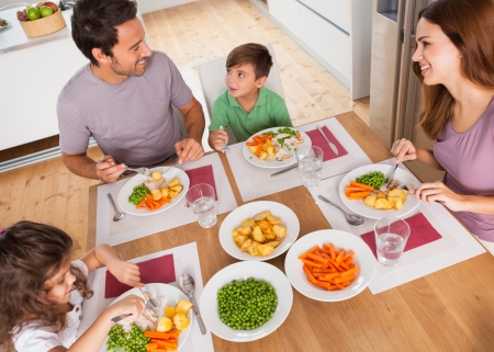 Family smiling around a healthy meal in kitchenの写真素材
