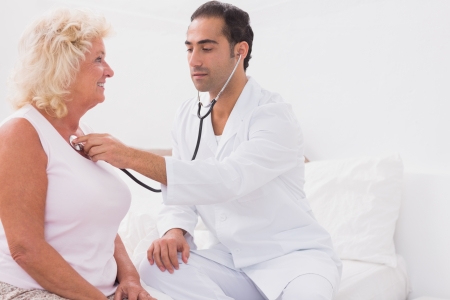 Doctor examining an old woman at homeの写真素材
