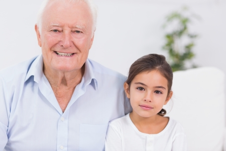Granddaughter and grandfather portrait sitting on the sofaの写真素材