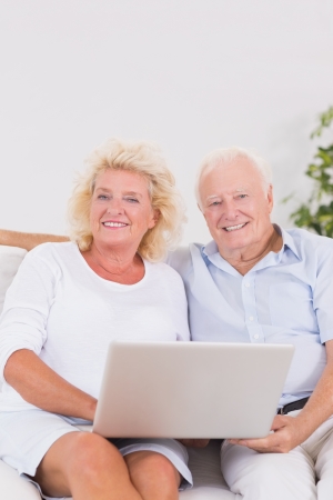 Aged couple using a laptop together sitting on the sofaの写真素材
