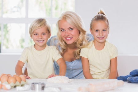Family smiling at the camera with the baking tools in kitchenの写真素材