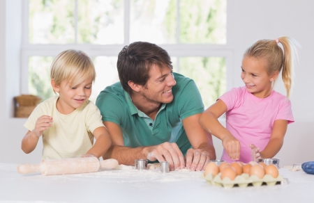 Father and his children cutting cookies out in the kitchenの写真素材