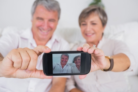 Old lovers taking a picture of themselves with smartphoneの写真素材