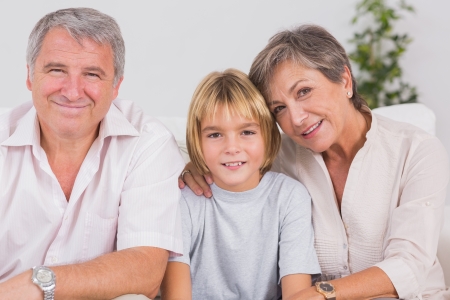 Portrait of a little boy and his grandparents smiling in sitting roomの写真素材