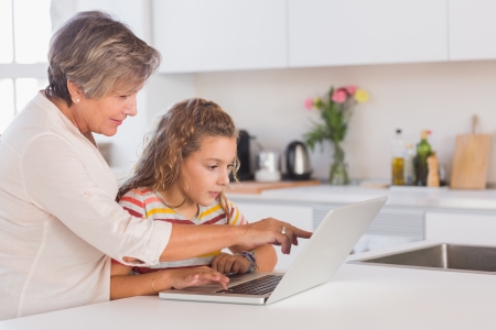 Grandmother and child looking at laptop in kitchenの写真素材