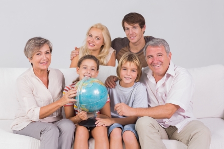 Family portrait looking at camera with a globe in sitting roomの写真素材
