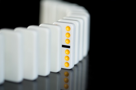One yellow domino in a line of white ones on black backgroundの写真素材