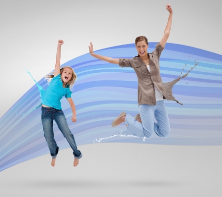 Woman and daughter jumping with clothes turning to paint splatters on blue wave backgroundの写真素材