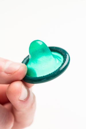 Hand holding green condom on white backgroundの写真素材