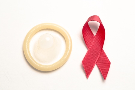 Red awareness ribbon and condom on white backgroundの写真素材