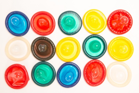 Many different coloured condoms on white backgroundの写真素材