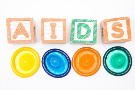 Wood blocks spelling out aids with four condoms on white backgroundの写真素材
