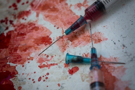 Two syringes lying on blood splatter on the floorの写真素材