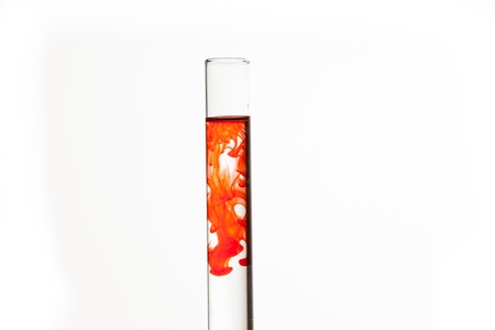Test tube of water with orange paint on white backgroundの写真素材