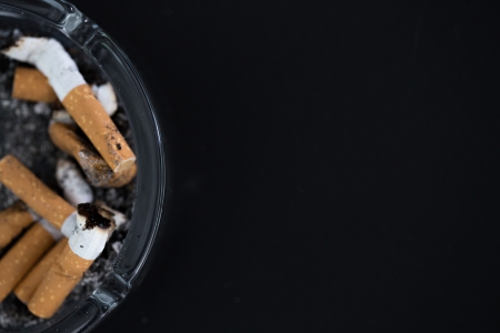 Ashtray full of butts with copy space on black backgroundの写真素材