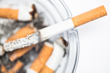 Close up of cigarette in ashtray on white background