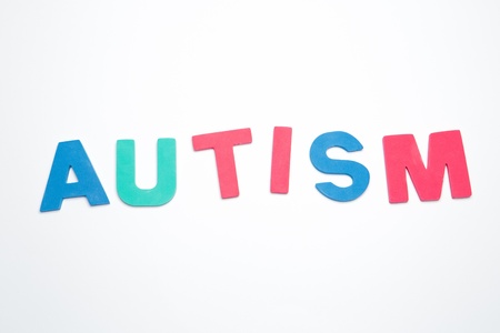 Autism spelled out in pink green and blue on white backgroundの写真素材