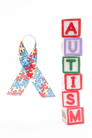 Autism awareness ribbon beside stacked blocks spelling autism on white backgroundの写真素材