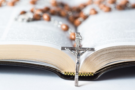 Cross of rosary beads resting against open bible