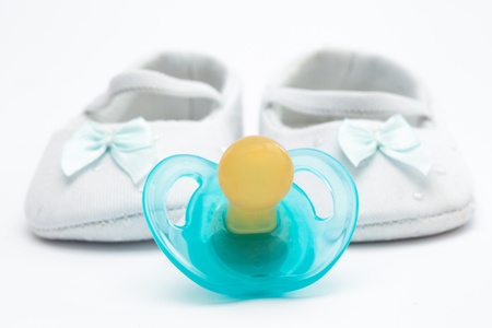 Blue soother with baby booties on white background