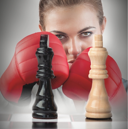 Female boxer with fists raised behind the chess boardの写真素材