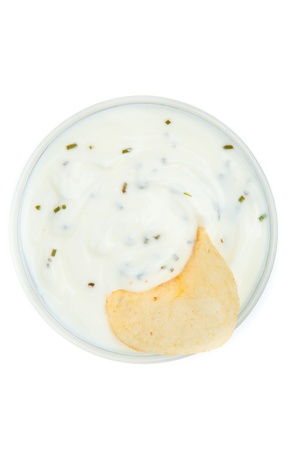 Close up of a bowl of white dip with herbs and a chips dipped in it against a white backgroundの写真素材