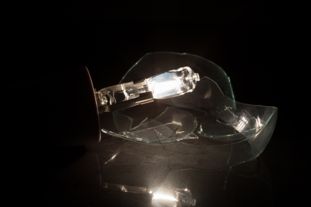 Glass of clear light bulb broken on black background on reflective surfaceの写真素材