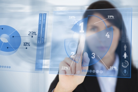 Serious businesswoman using blue pie chart futuristic interface by touching itの写真素材