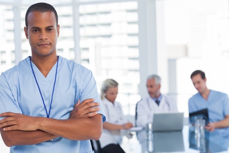 Serious doctor with arms crossed standing in front of his team