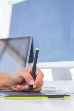 Male hand drawing on graphics tablet on white deskの写真素材