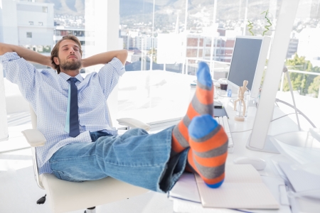 Designer relaxing at desk with no shoes and stripey socksの写真素材