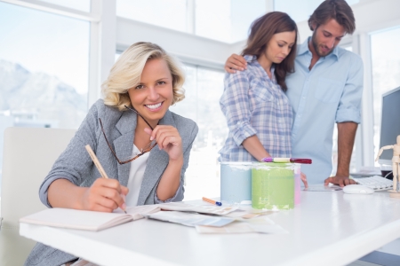 Smiling designer looking at the camera while a couple is choosing an interior の写真素材