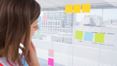 Woman looking at sticky note in creative officeの写真素材