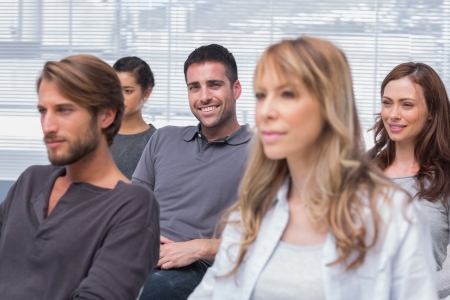 Patients listening in group therapy with one man smiling at the camera in officeの写真素材