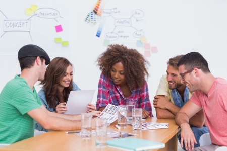 Creative team going over contact sheets in meeting in office with whiteboard Creative team going over contact sheets in meeting in office with whiteboard