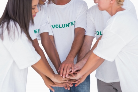 Happy volunteers putting hands together on white backgroundの写真素材
