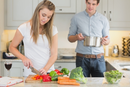 Man helping woman with cooking in kitchenの写真素材