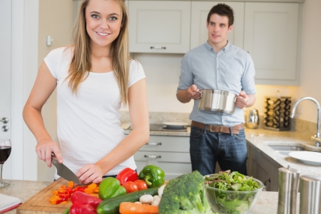 Woman preparing vegetables with man helping in kitchenの写真素材