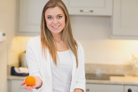 Woman with orange in her hand in kitchenの写真素材