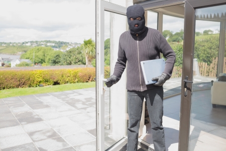 Burglar holding laptop and leaving homeの写真素材